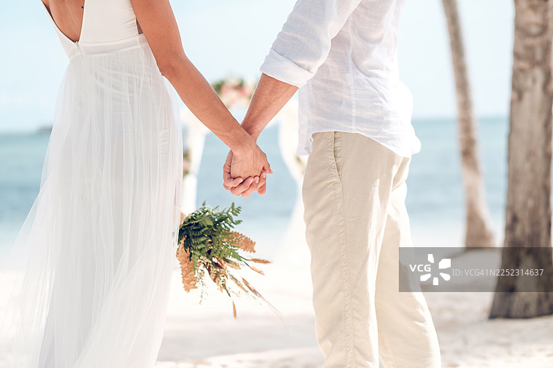 情侣在热带海滩婚礼仪式上牵手图片素材