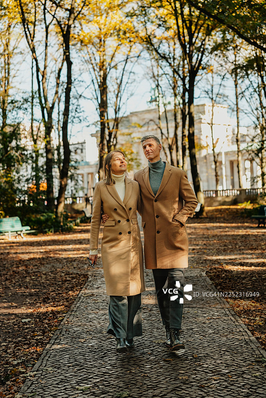 秋季，一对情侣漫步在柏林美丽的公园里，周围是树木和落叶。图片素材