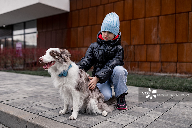 孩子与狗在城市人行道上享受寒冷天气外出图片素材