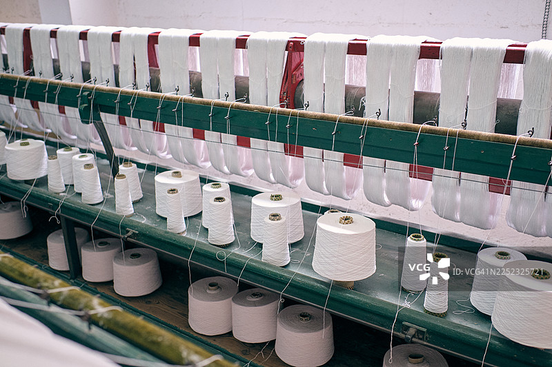 老式纺织厂机器正在纺白色棉纱图片素材