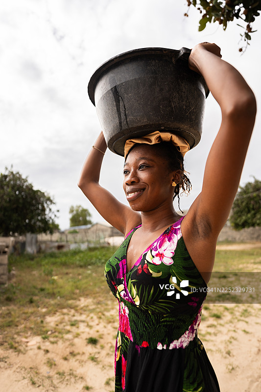 一位塞内加尔非洲妇女头顶水桶图片素材