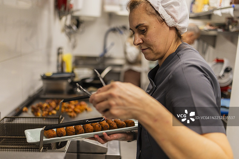 女厨师在商业厨房准备炸肉饼图片素材