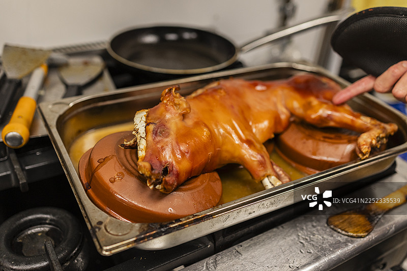 厨师之手在厨房里烤乳猪图片素材