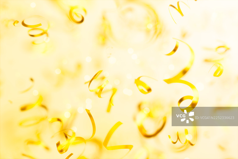 金色的圣诞纸屑和彩带飘落在一个明亮喜庆的背景上。适用于新年、生日、婚礼或奢华派对的优雅庆典概念。抽象的金色节日背景，带有复制空间。图片素材