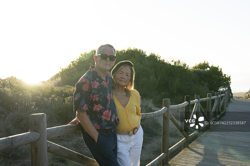 日落时分，海滩木栈道上的一对老年夫妇肖像图片素材