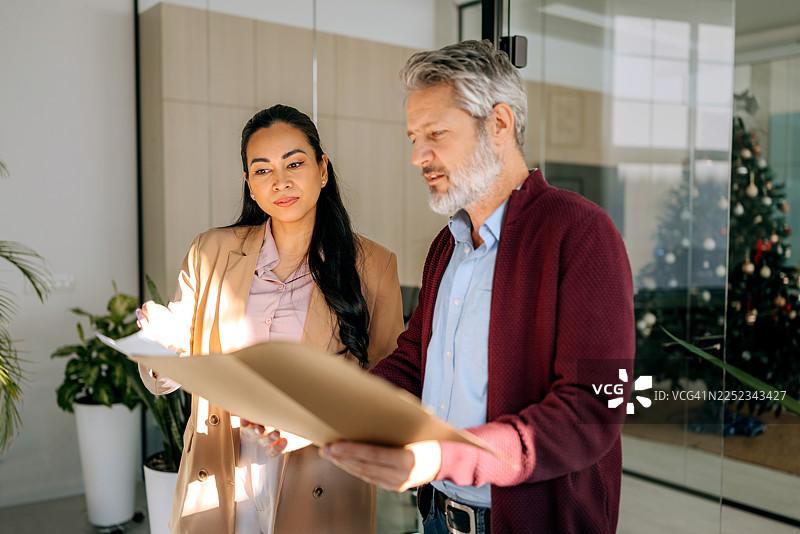 同事们在办公室边走边查看文件图片素材