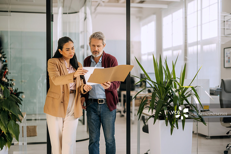 同事们在办公室边走边审阅文件图片素材