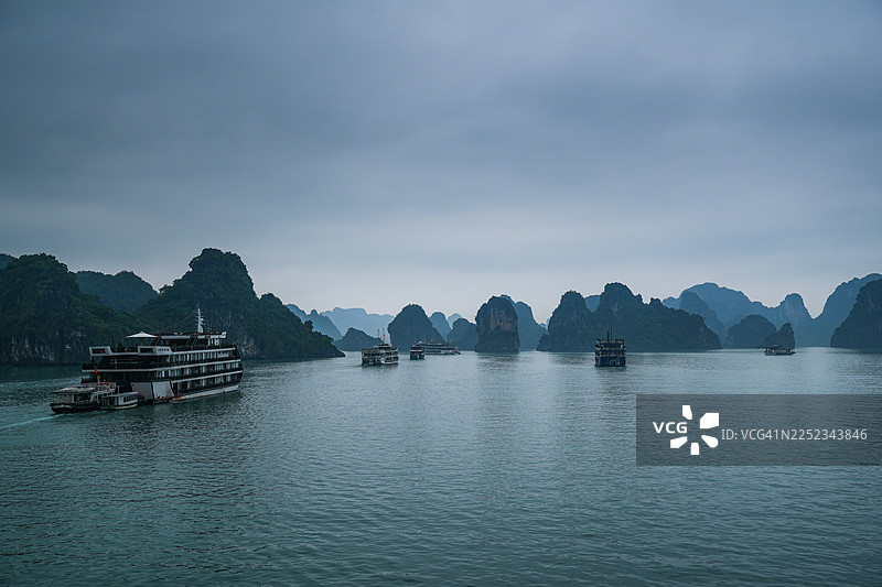 白龙湾标志性岛屿的大气景观，翠绿的海水在偶尔有游轮穿梭的高耸山峰之间流淌。图片素材