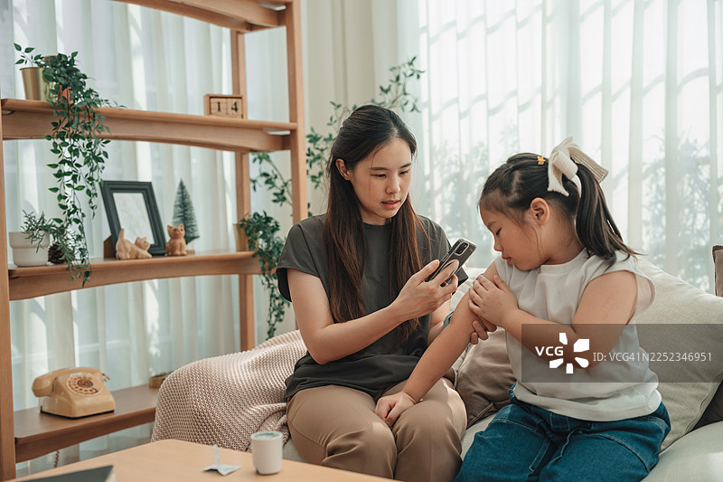 现代妈妈使用CGM设备检查女儿的血糖水平图片素材