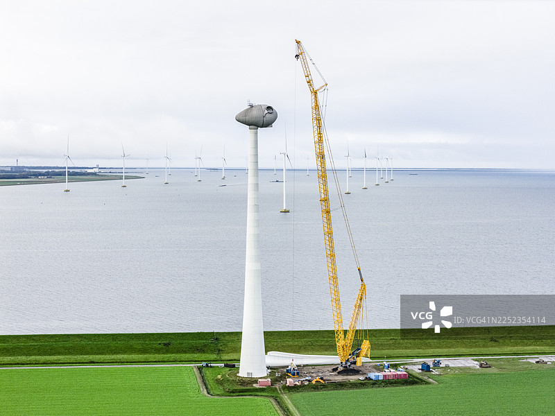 风力发电场内，巨大的起重机正在进行风力涡轮机的建造图片素材