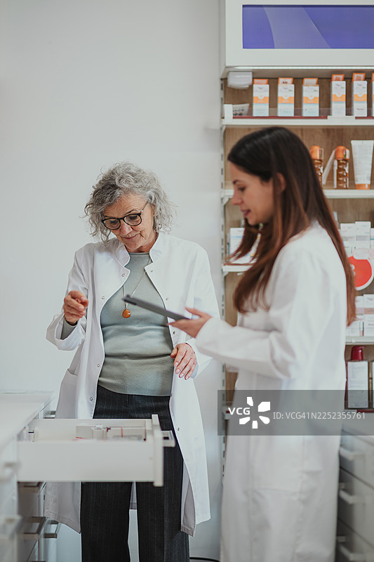 药剂师们在药房内协作，使用平板电脑进行库存盘点图片素材