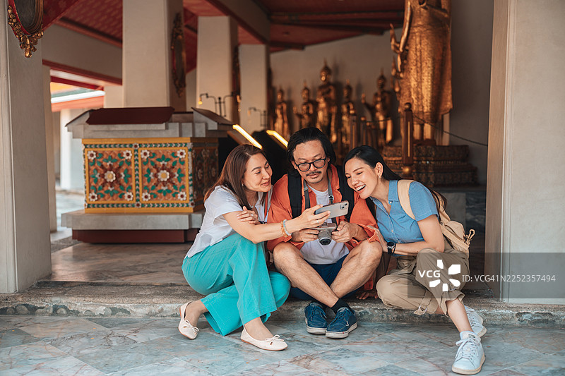 一群成熟的朋友在探索寺庙时，正用智能手机快速预订酒店图片素材