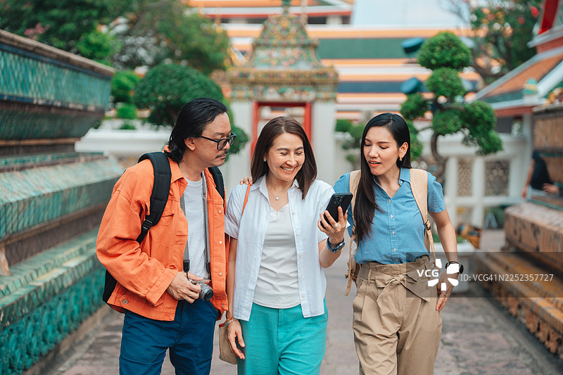 一群成熟的朋友一起探索寺庙，边走边用智能手机了解其历史，穿梭于错综复杂的建筑之中图片素材