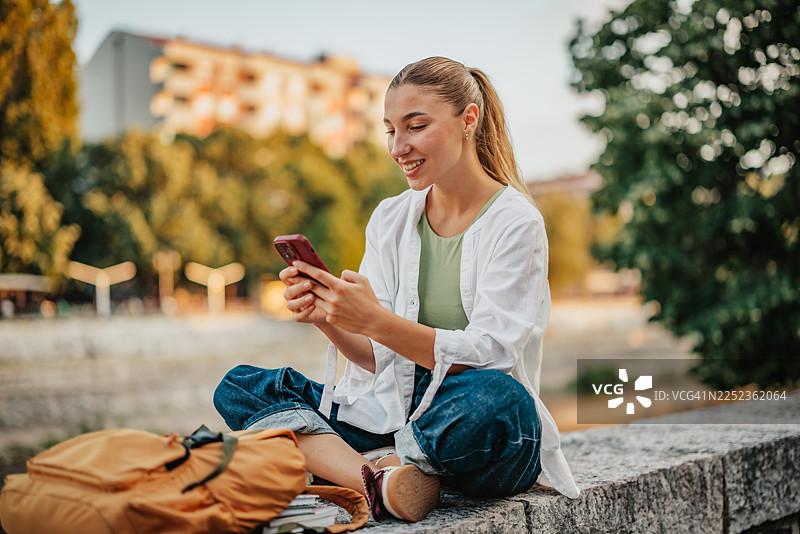学生在大学课程间隙的校园里使用智能手机图片素材