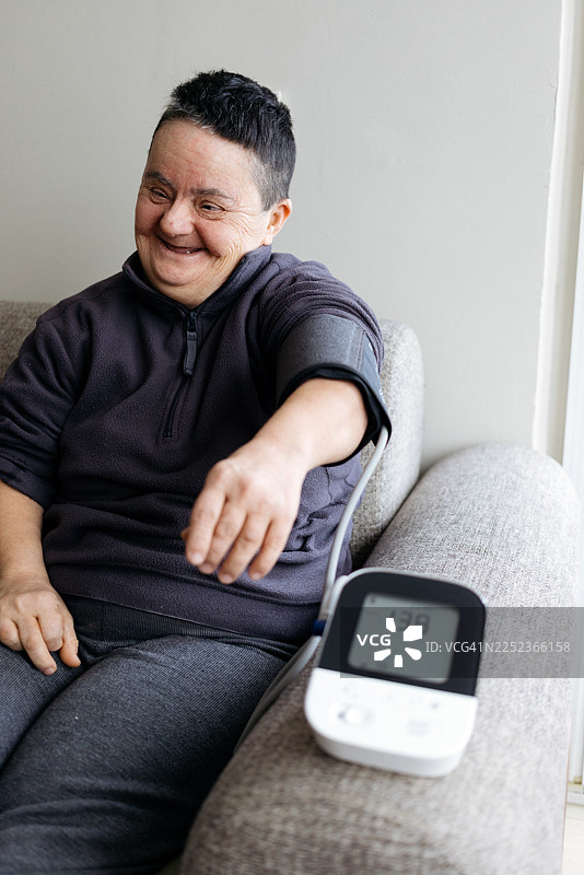 患有唐氏综合征的老年女性正在测量血压图片素材