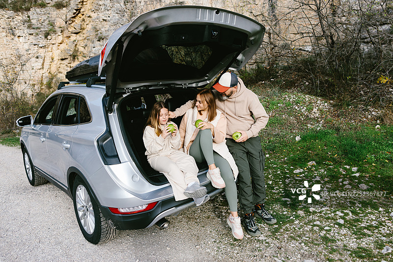 一家人在公路旅行中休息，坐在敞开的汽车后备箱里图片素材