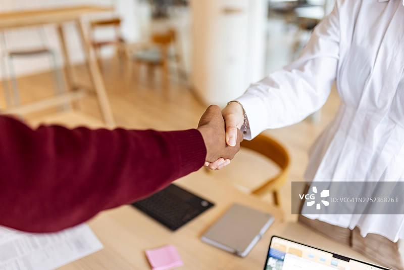 两位同事握手，象征着在现代办公室的协议与专业合作图片素材