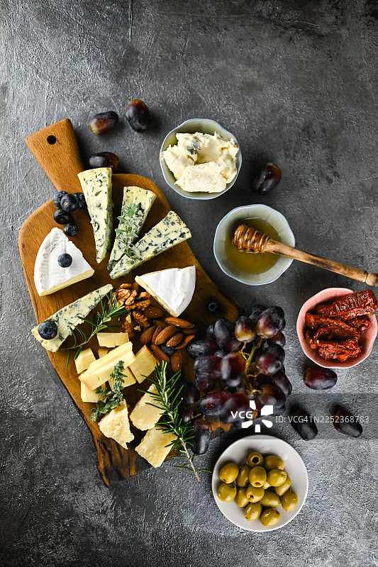 在质朴的木板上摆放着美味的各种美食奶酪、葡萄和坚果图片素材