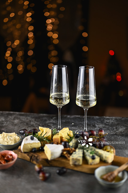 木制桌上的两杯香槟和奶酪板图片素材