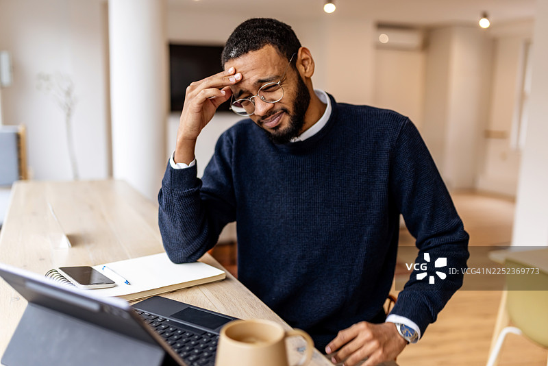 一位男士在办公室的木制书桌前，因工作任务而感到压力重重，陷入沉思图片素材