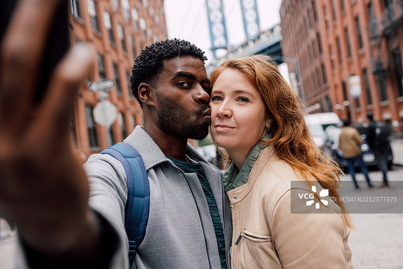 情侣在纽约杜姆博区拍摄自拍时亲吻图片素材