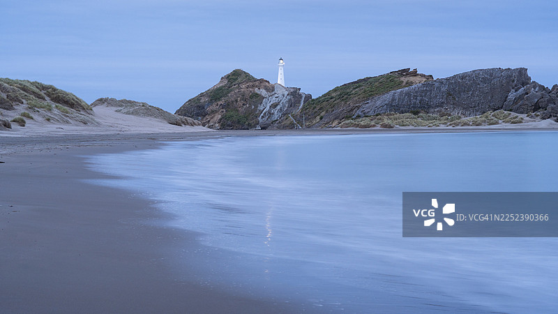 新西兰北岛惠灵顿地区怀拉拉帕海岸卡斯尔波因特，岩石上的卡斯尔波因特灯塔和解放湾，海洋，长曝光，傍晚，灯光明亮。图片素材