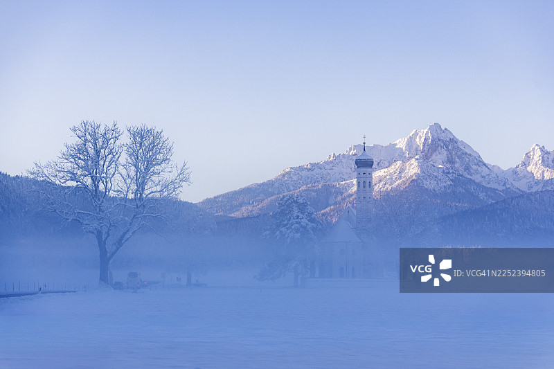 雪山风景，前景为圣科洛曼朝圣教堂，背景为雾气，德国巴伐利亚州阿尔高地区福森附近肖万高图片素材