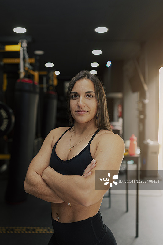 自信的女运动员交叉双臂站在健身房里图片素材