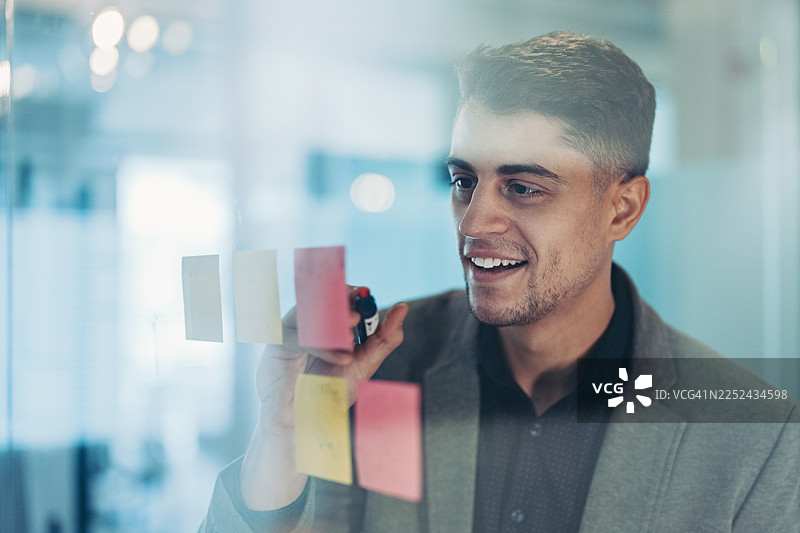 年轻的商人正在窗户上写笔记图片素材