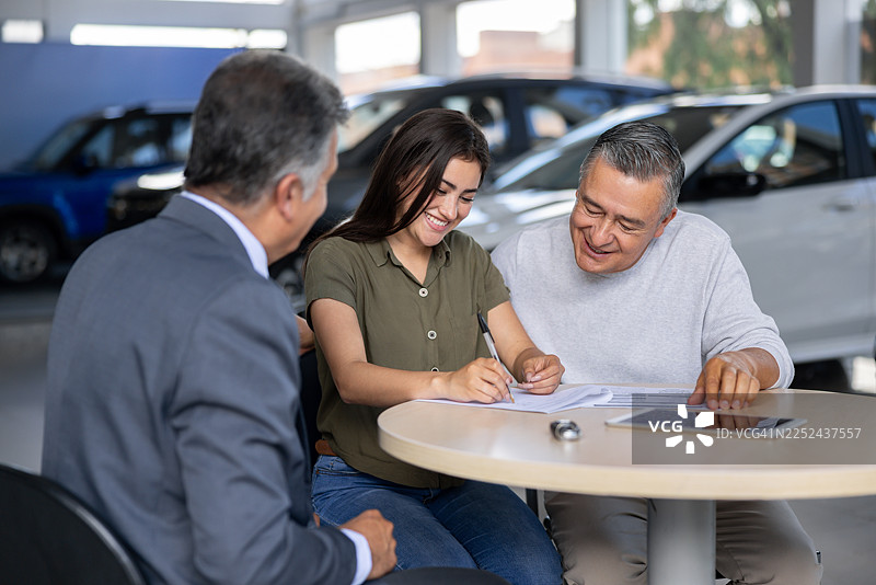 一位快乐的女士在经销商处购车后签署合同图片素材