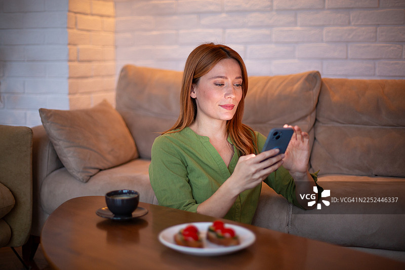 年轻女子在家放松地使用智能手机图片素材
