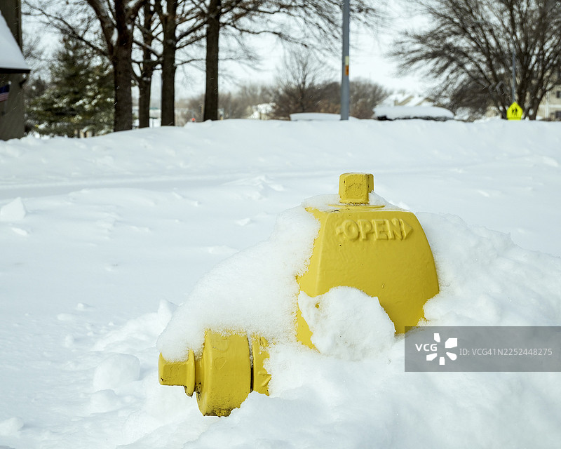 冬日里，一个明亮的黄色消防栓半埋在厚厚的雪中，位于美国衣阿华州西得梅因市。图片素材