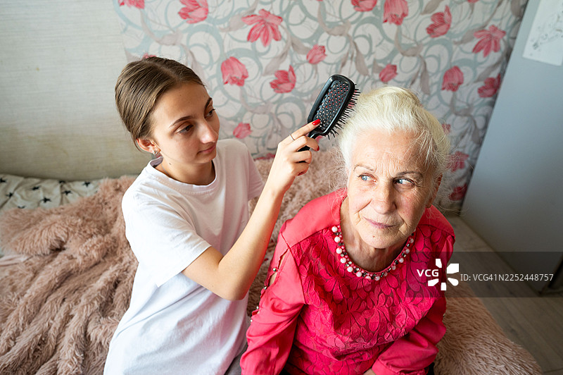 年轻女子在家为一位年长女子梳头图片素材