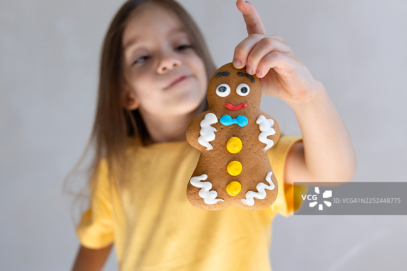 快乐的小女孩肖像，手里拿着装饰好的姜饼，庆祝节日季图片素材