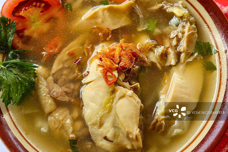 一碗丰盛的鸡肉索托特写，这是一种传统的印度尼西亚汤，上面撒有炸葱头、番茄和新鲜香草图片素材