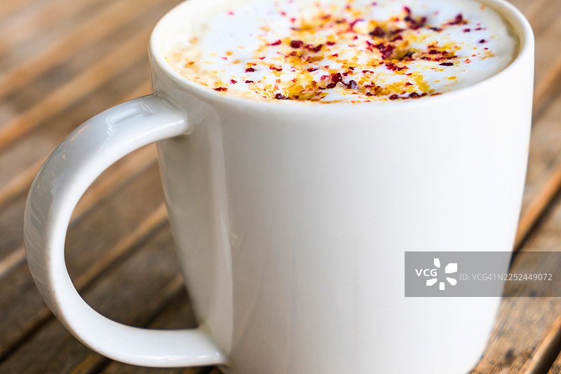 木桌上带有拉花艺术的白色咖啡杯特写，适合惬意的早晨或休息时光图片素材