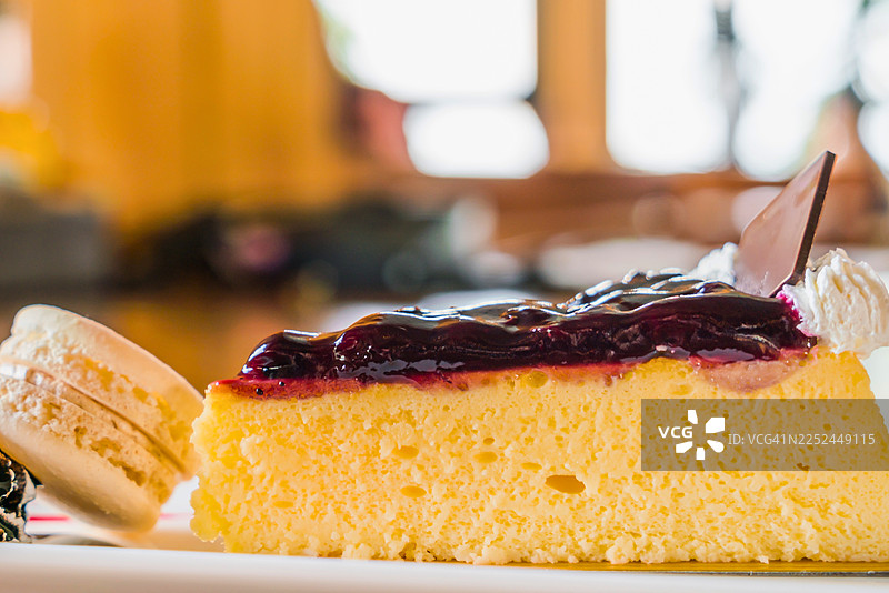 美味的芝士蛋糕切片，配有蓝莓酱和鲜奶油，旁边还有马卡龙图片素材