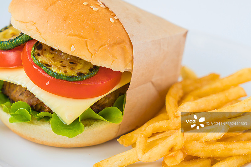 美味的手工汉堡，配有烤西葫芦、番茄、奶酪和新鲜生菜，旁边是酥脆的炸薯条。图片素材
