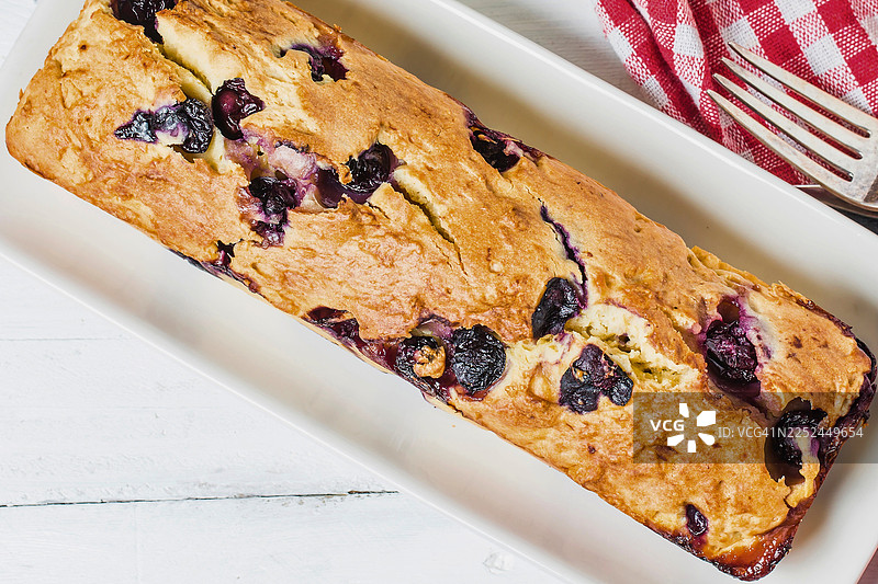 美味的手工蓝莓磅蛋糕放在一张白色木桌上，旁边有一块格子餐巾图片素材