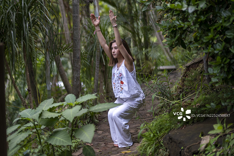 年轻女子在宁静的自然环境中做瑜伽，做出各种姿势和伸展动作。图片素材
