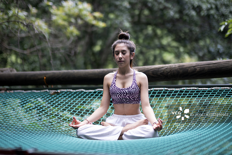 年轻女子在宁静的自然环境中做瑜伽，摆出各种姿势和伸展动作。图片素材