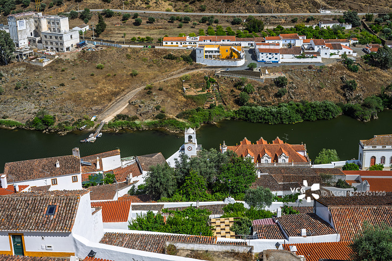 俯瞰葡萄牙河边一座历史悠久的村庄，村庄内有传统房屋和教堂，坐落于山谷中，天空晴朗。图片素材