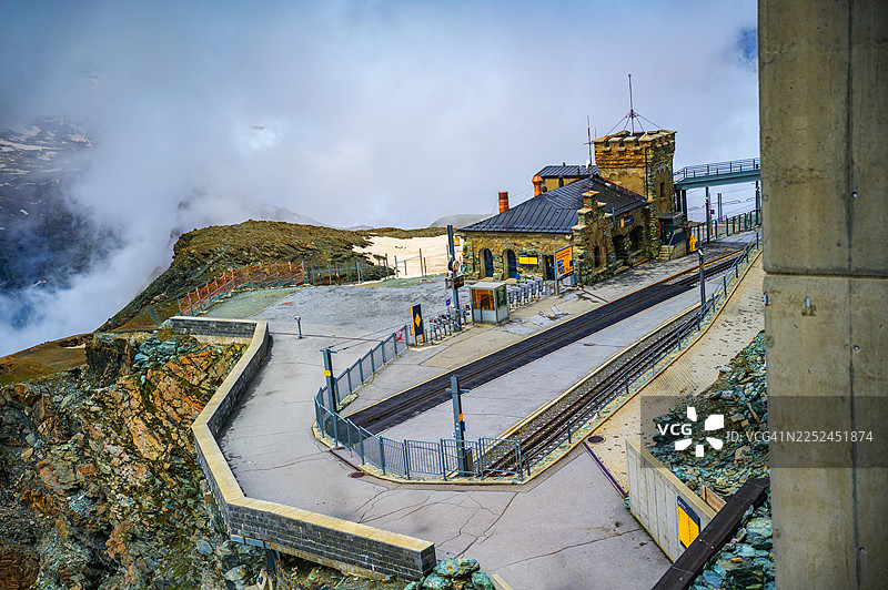 高角度拍摄的，隐藏在云雾中的历史悠久的山区火车站，坐落在岩石山峰之间，拥有壮丽的景观图片素材