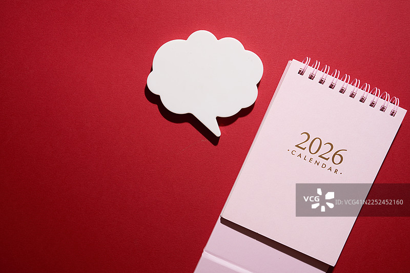 鲜艳的红色背景上的2026年台历和空白对话气泡，随时准备添加您的信息或新年目标图片素材