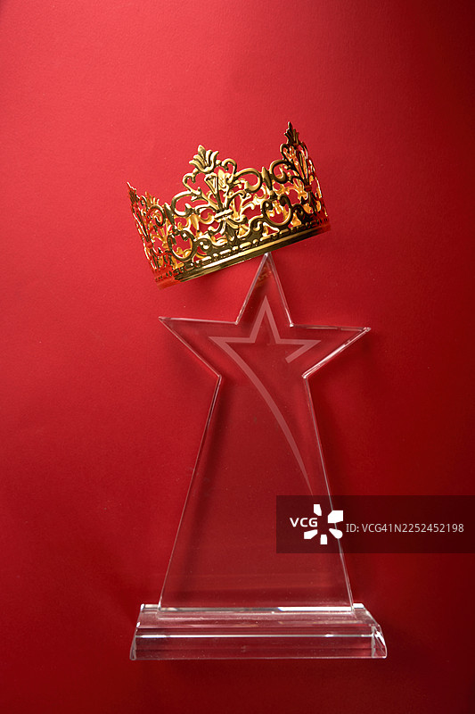金色皇冠和星星奖在充满活力的红色背景上，象征着成就和成功图片素材