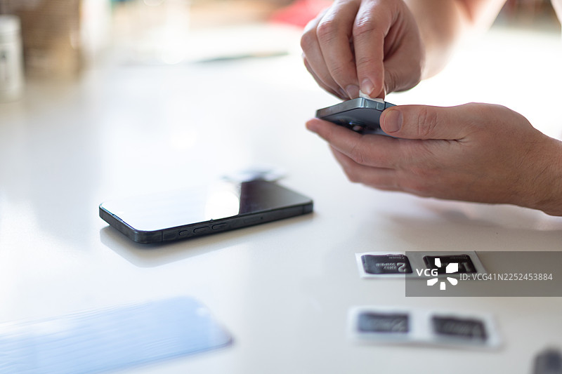 白桌上，一只手正在清洁手机的相机镜头图片素材