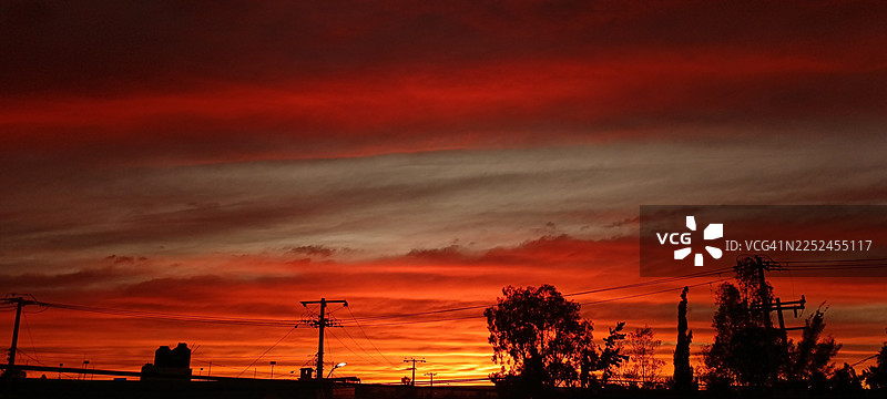 维多利亚·德·兰戈，墨西哥，托尔特卡斯步行街，电力线和树木剪影下的戏剧性红色日落天空图片素材