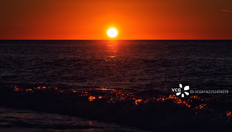 佐治亚州，宁静海面上色彩鲜明的橙色日落，波光粼粼的海浪图片素材