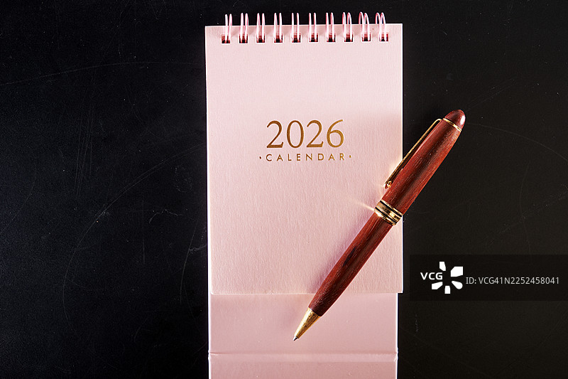 2026年台历和钢笔，置于深色背景上，用于规划和安排日程图片素材