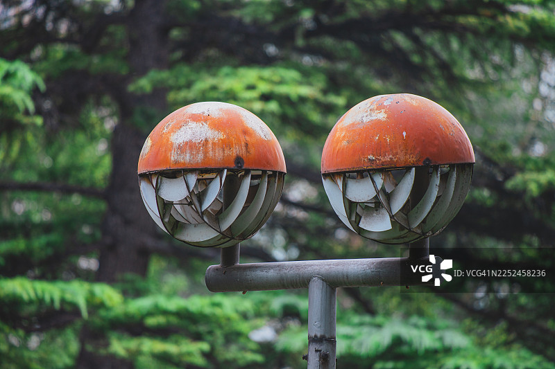 两个锈迹斑斑、球形的街灯，几何设计，背景是模糊的绿色森林图片素材
